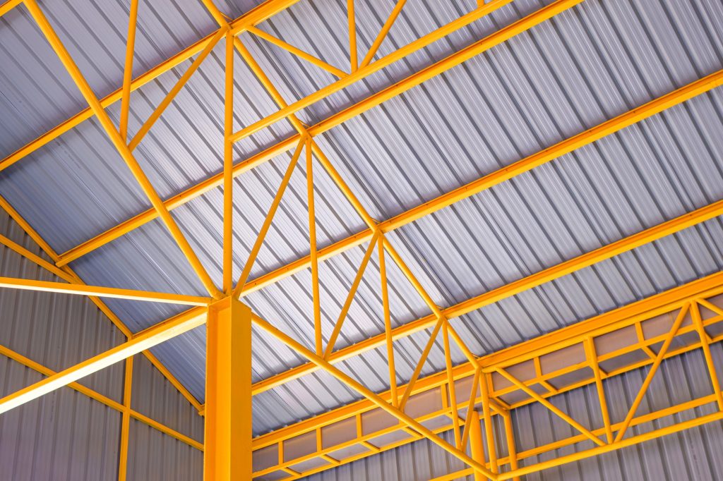 Yellow metal roof beams structure and aluminum corrugated tile roof of industrial building